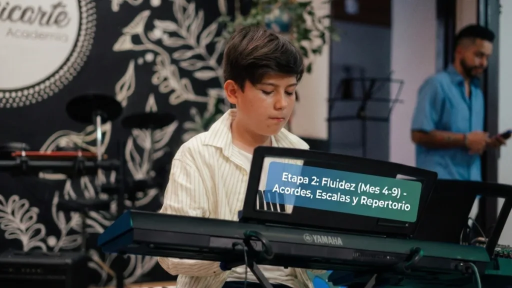 Estudiante joven practicando en la Academia Musicarte frente al mural artístico de la marca, ilustrando la Etapa 2 de Fluidez (Mes 4-9) para aprender acordes y escalas.
